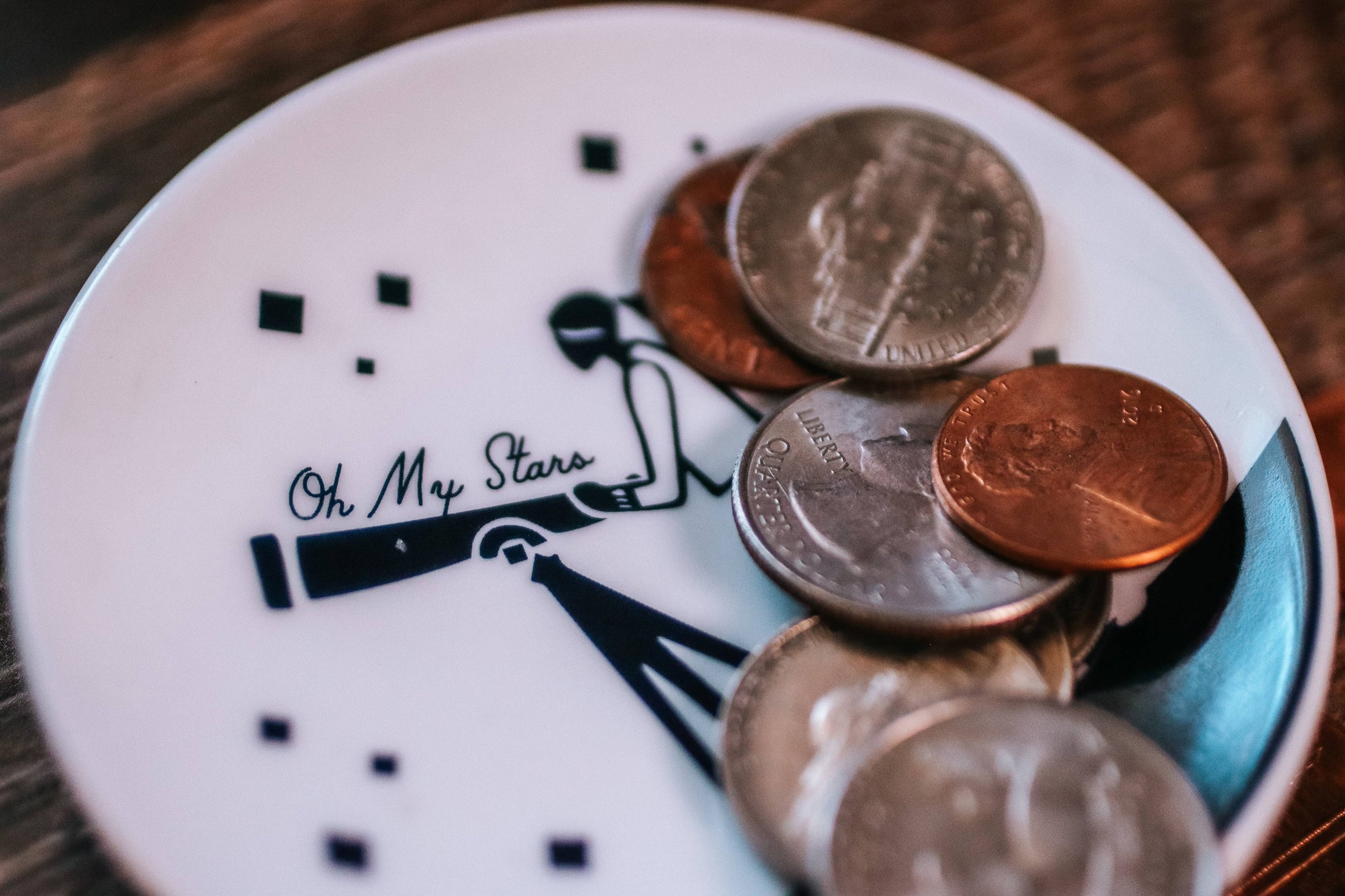Stack of coins on a decorative plate with 'Oh My Stars' text
