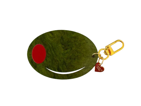 Green pimento olive shaped keychain with gold hardware and a heart-shaped gold charm that reads "a shop of things" 