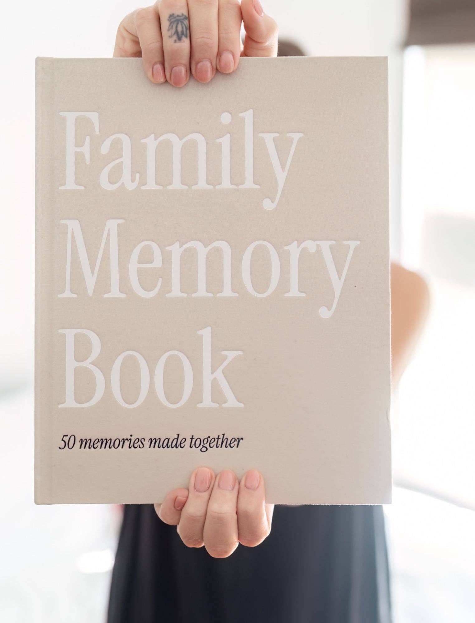 Person holding a 'Family Memory Book' with text on a neutral background