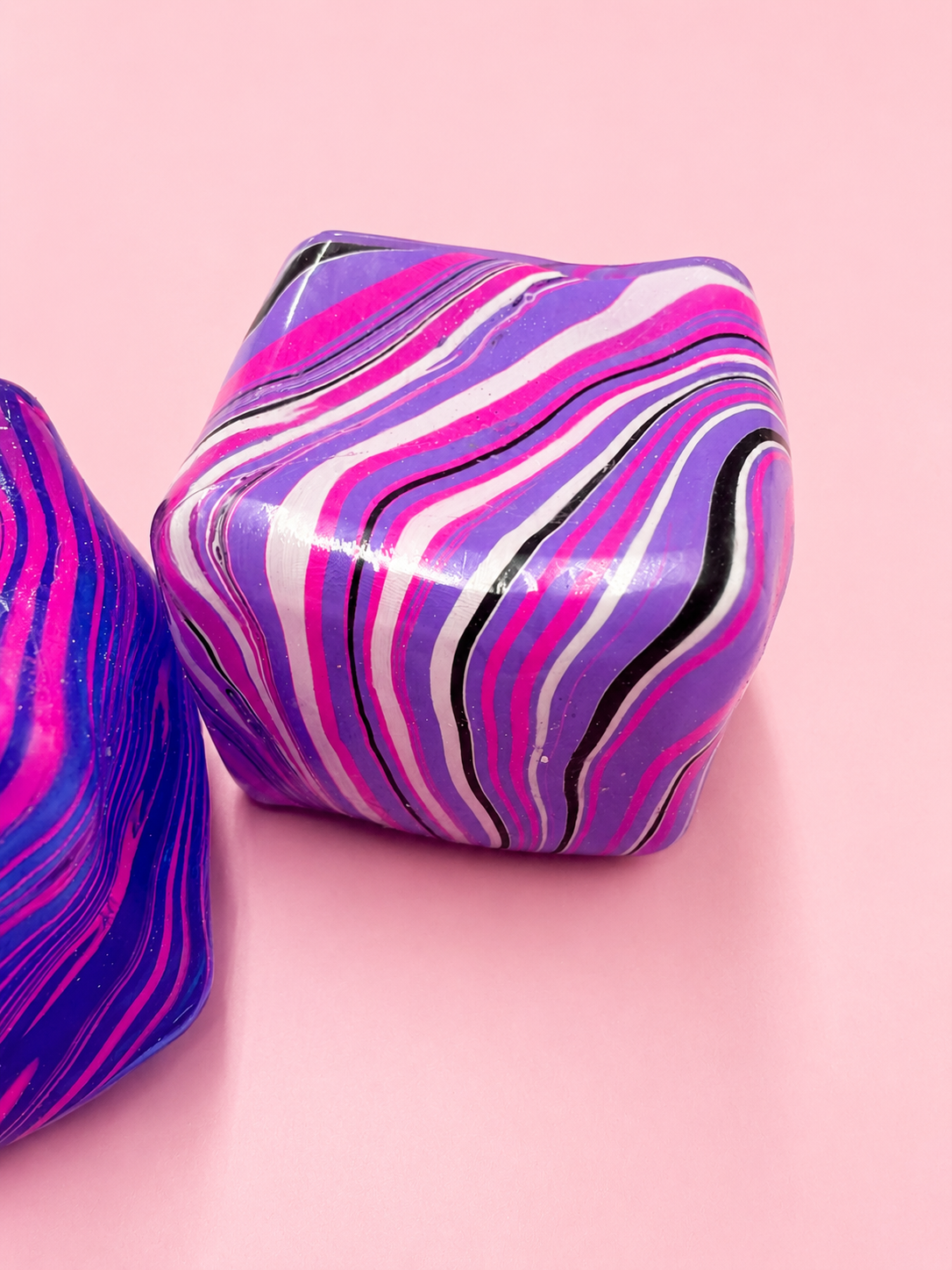 Colorful marbled cylindrical objects on a pink background