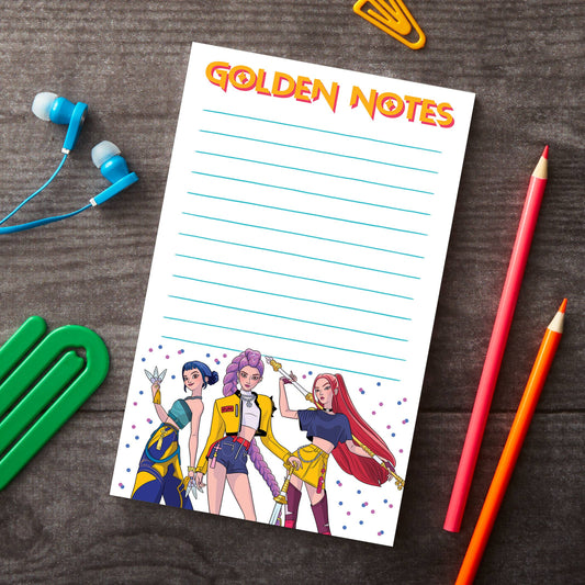 Notepad with 'Golden Notes' text and colorful illustrations of three characters on a wooden surface with stationery items.
