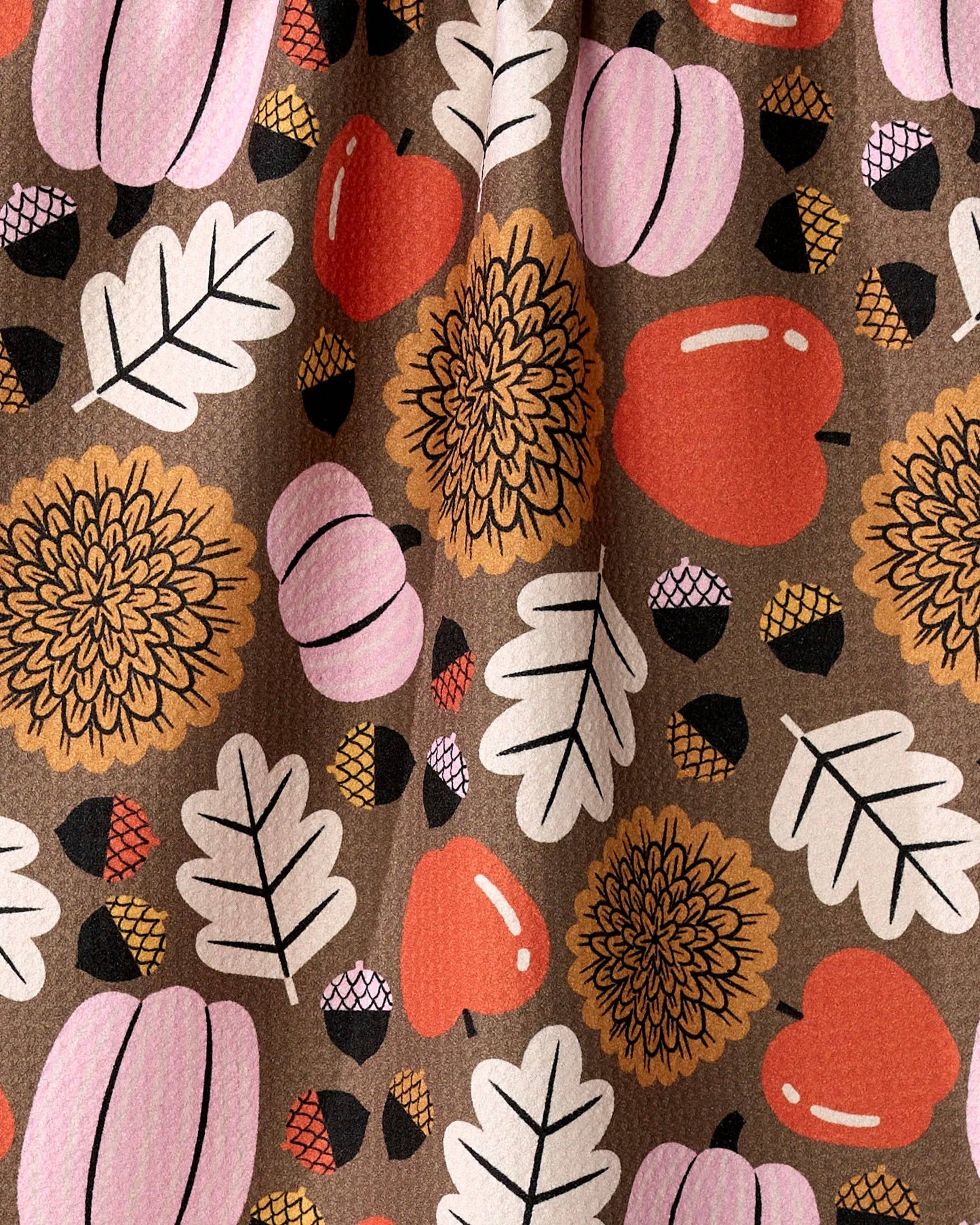 Patterned fabric with pumpkins, leaves, and flowers on a brown background