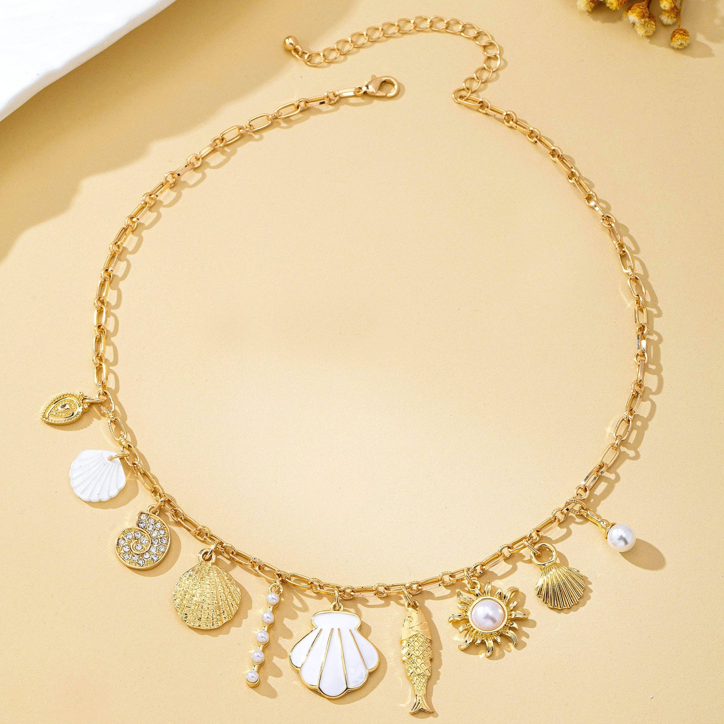 Gold necklace with various charms on a beige background