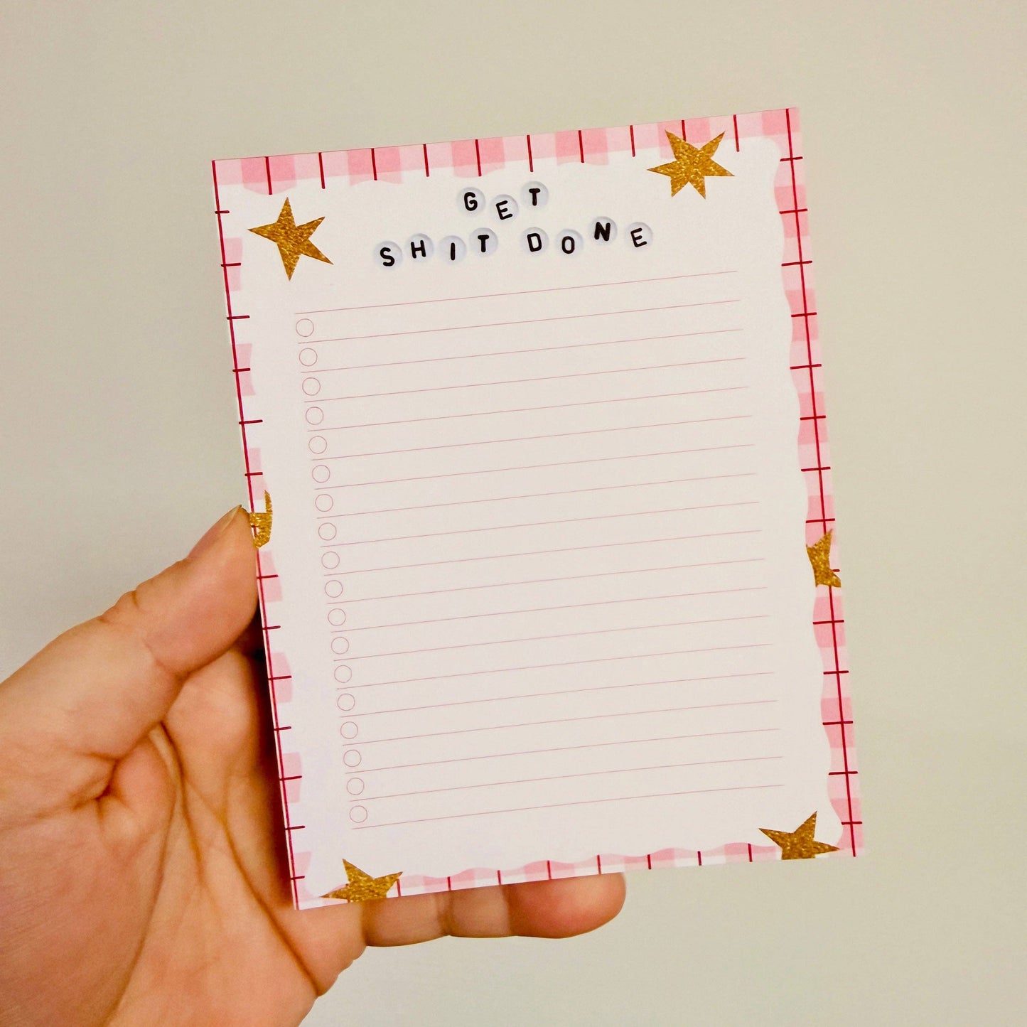 Hand holding a notepad with 'GET SHIT DONE' text and star designs.