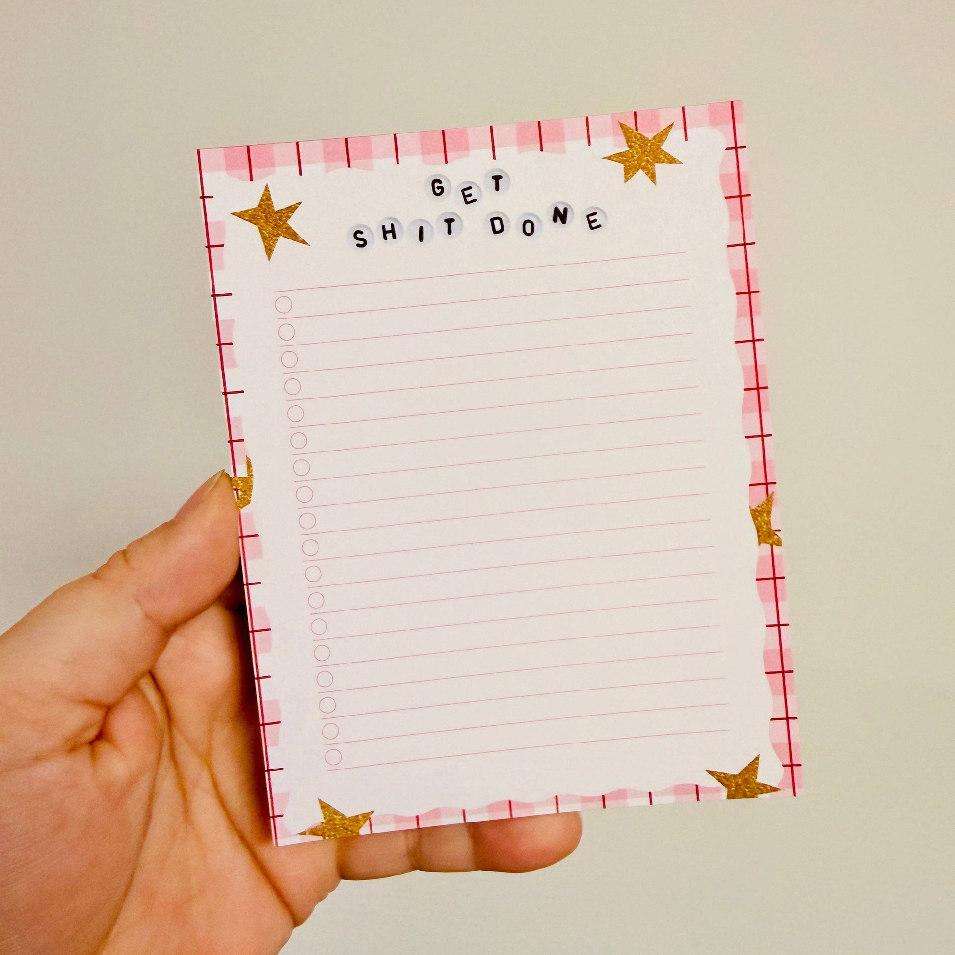Hand holding a notepad with 'GET SHIT DONE' text and star designs.