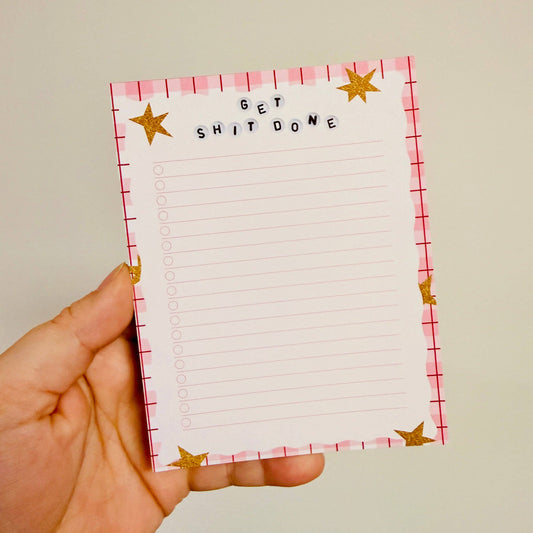 Hand holding a notepad with 'GET SHIT DONE' text and star designs.