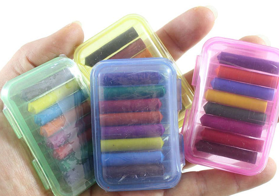 Set of colorful mini crayons in transparent cases held in a hand against a white background