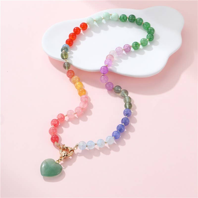 Colorful beaded necklace with a heart pendant on a pink background