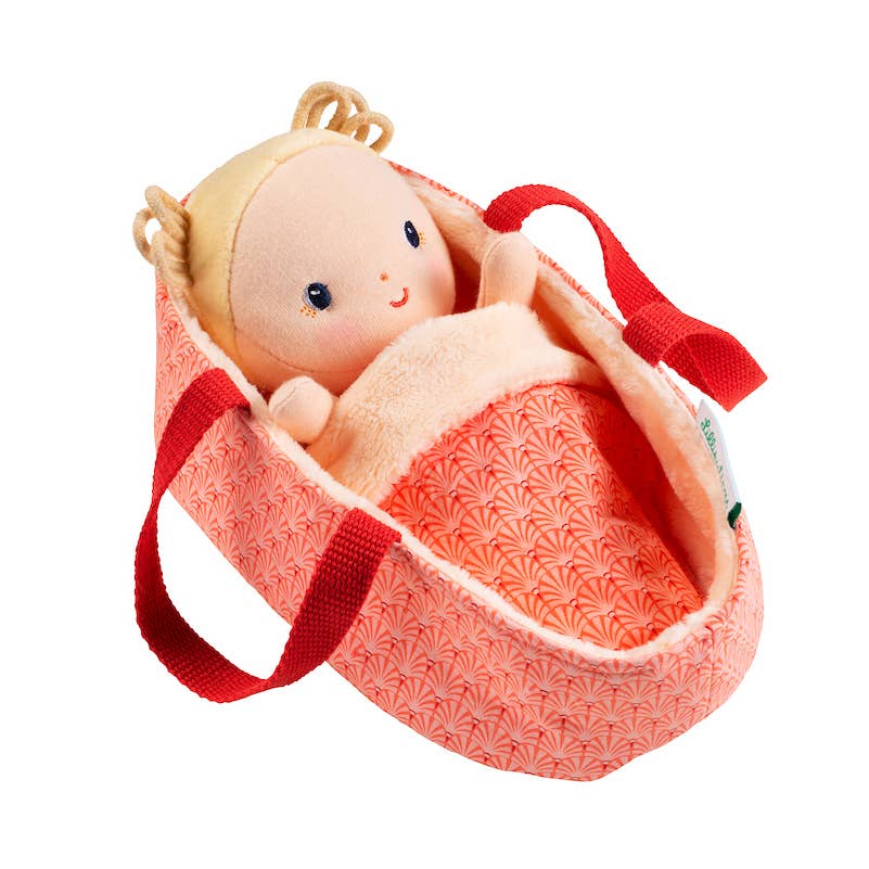 Baby doll in a pink and red patterned bag on a white background