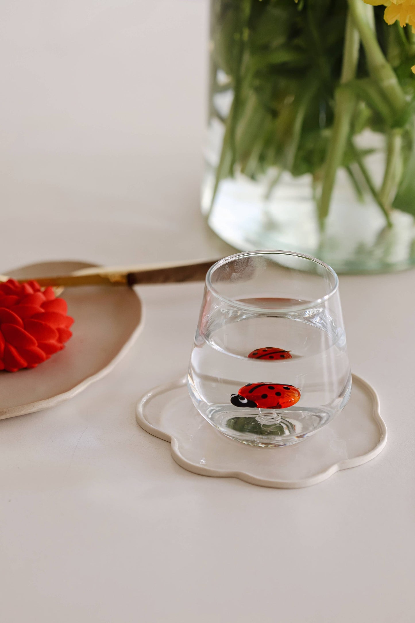 glass with small lady bug figurine in the center of it sitting on a white tray