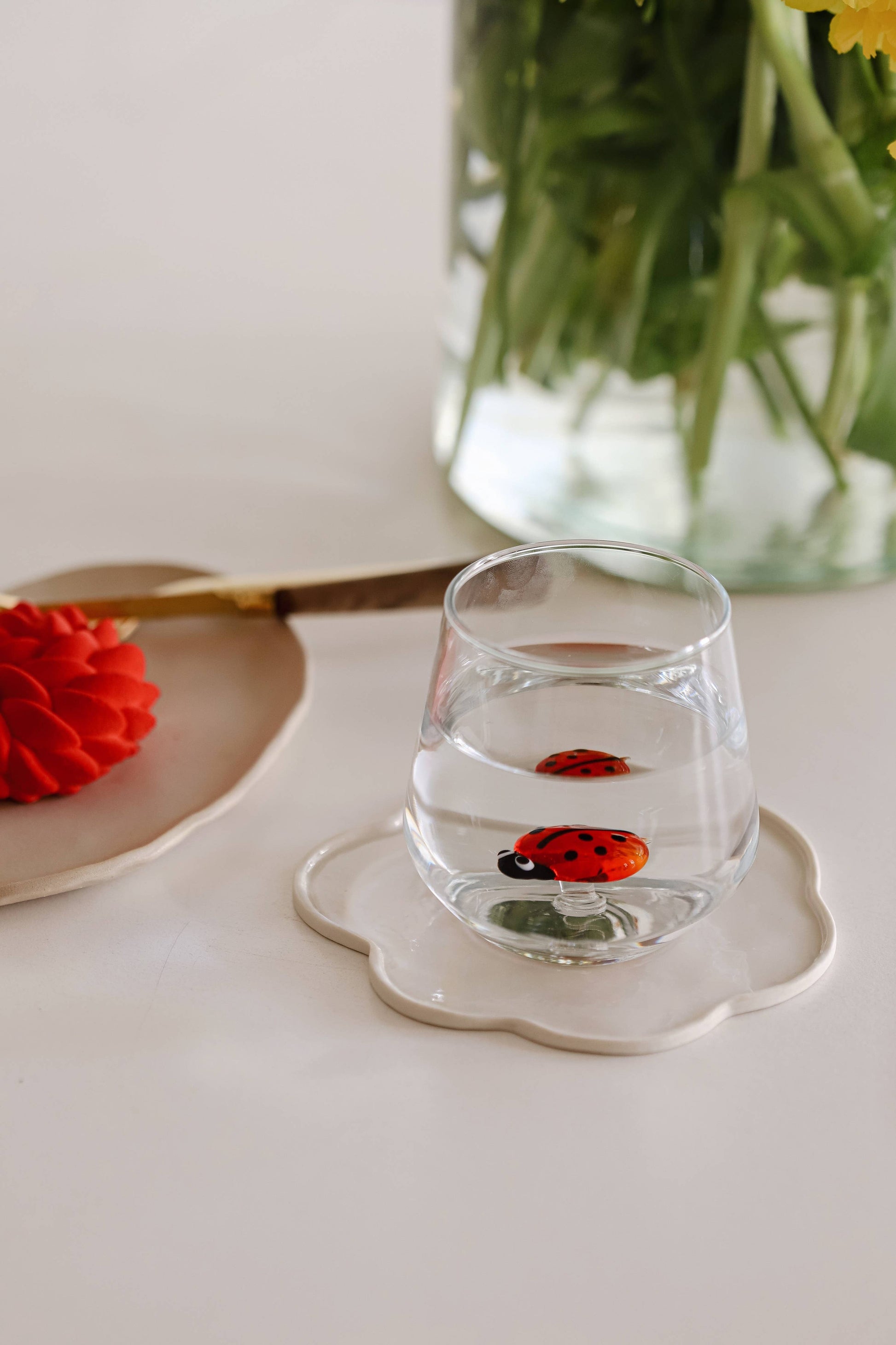 glass with small lady bug figurine in the center of it sitting on a white tray