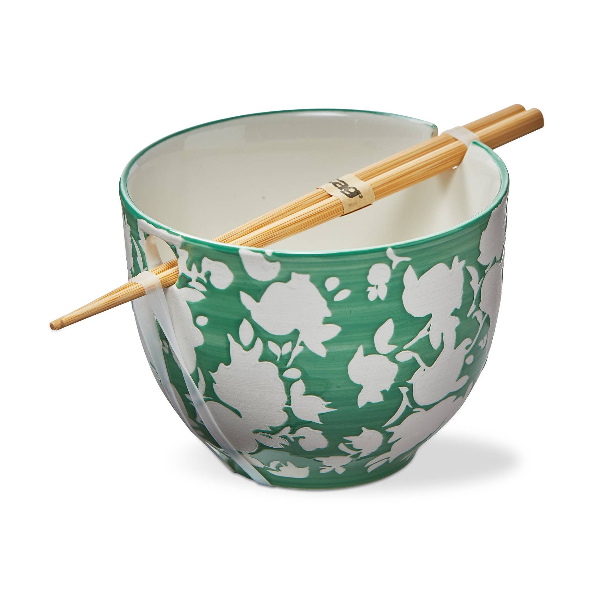 A green noodle bowl with a white floral pattern. Flowers are silhouette shapes with no detail. The interior of the bowl is white. A pair of chopsticks rest in the dedicated spot for storing chopsticks atop the bowl. On a white background.