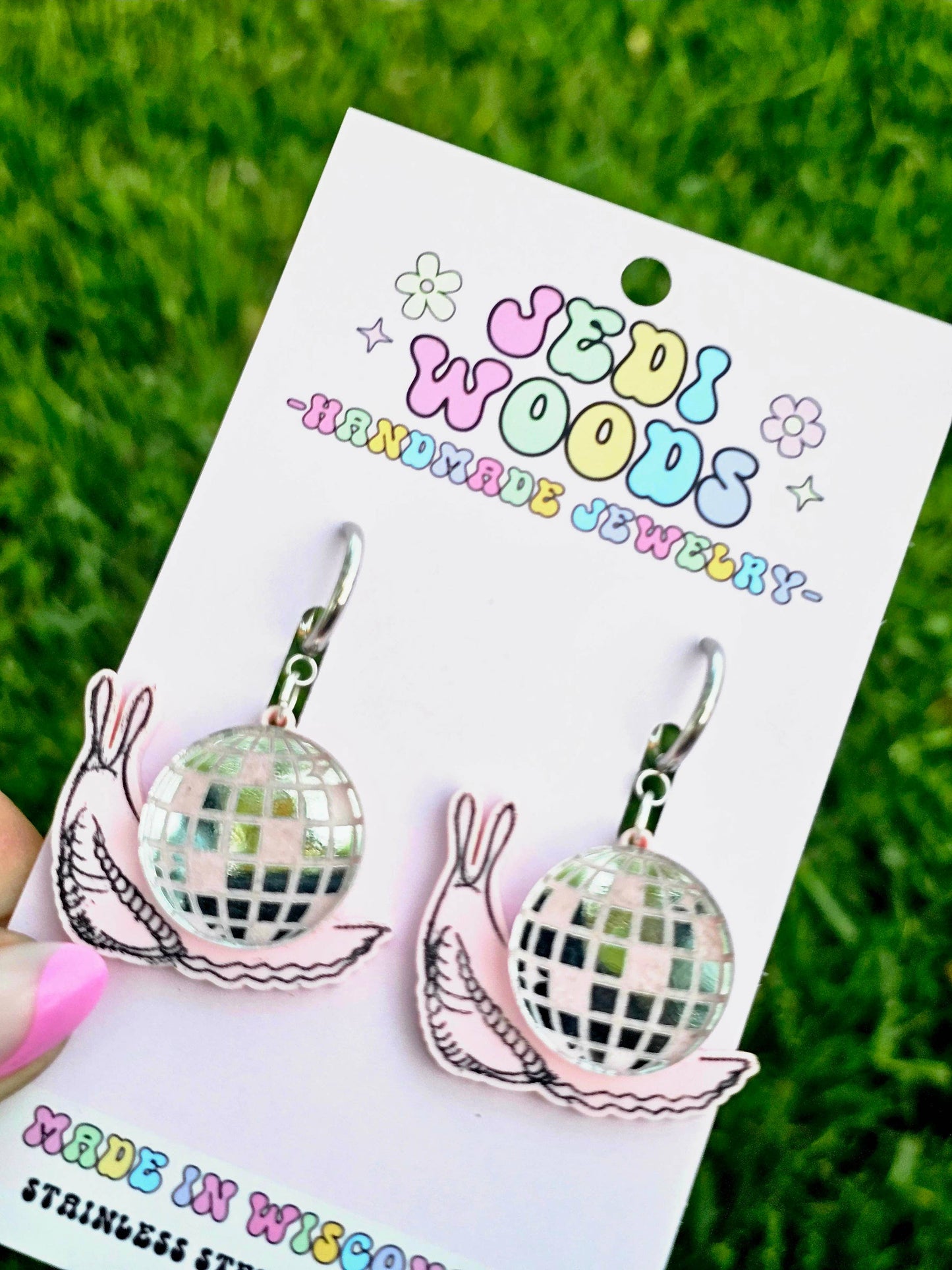 Discord earrings on a Udi Woods branded card with grass in the background