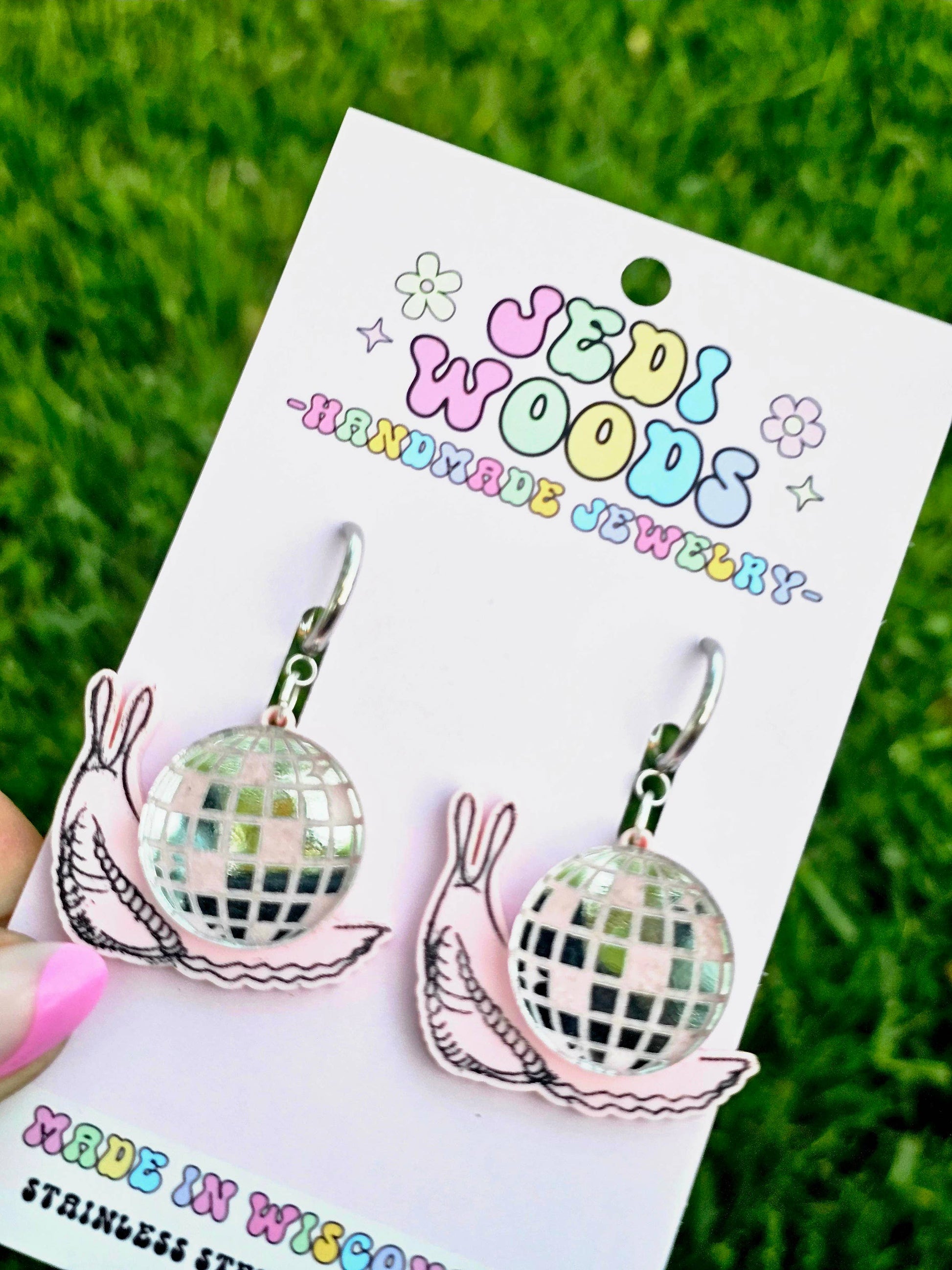 Discord earrings on a Udi Woods branded card with grass in the background