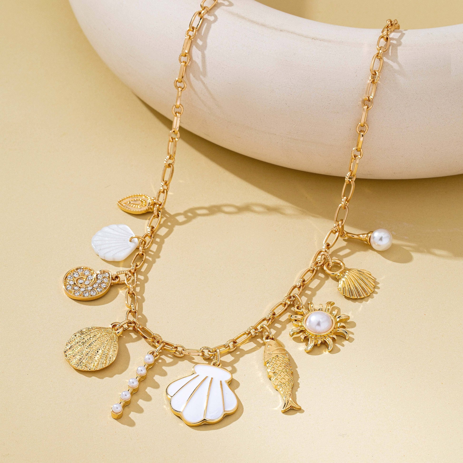 Gold necklace with various charms on a beige background
