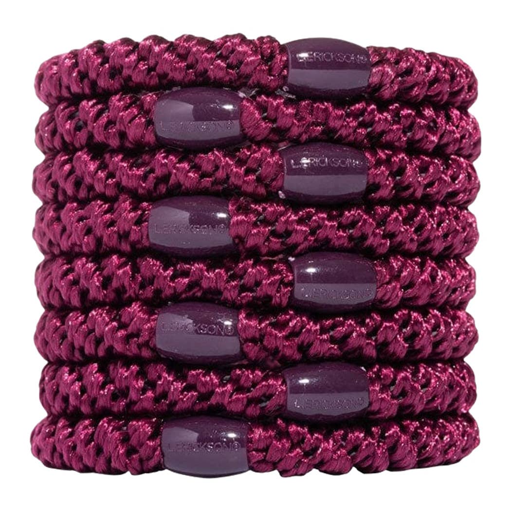 A stack of six magenta braided elastic wristbands with dark purple oval plastic caps, shown on a plain white background.