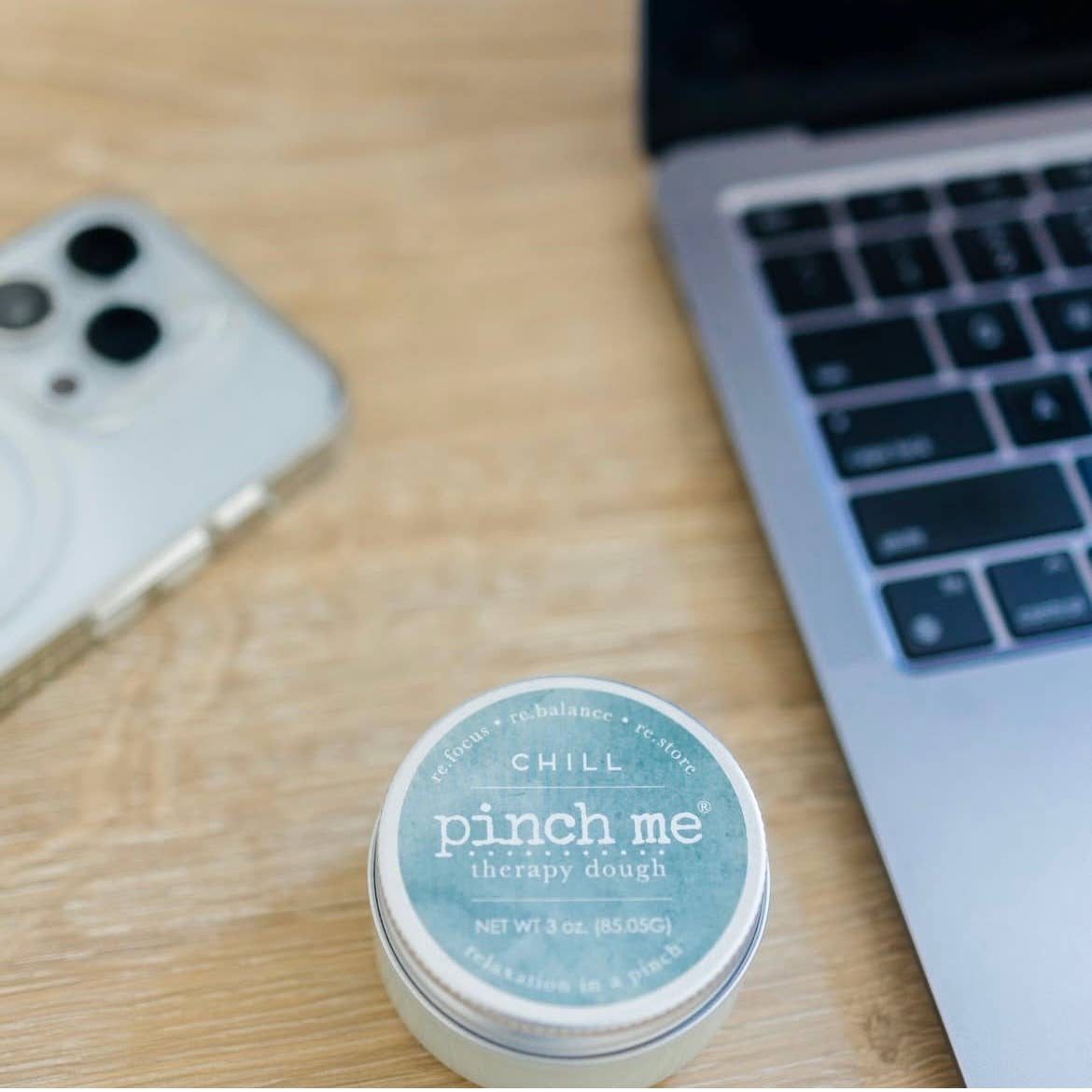 Pinch Me Therapy Dough container on a desk with a laptop and phone