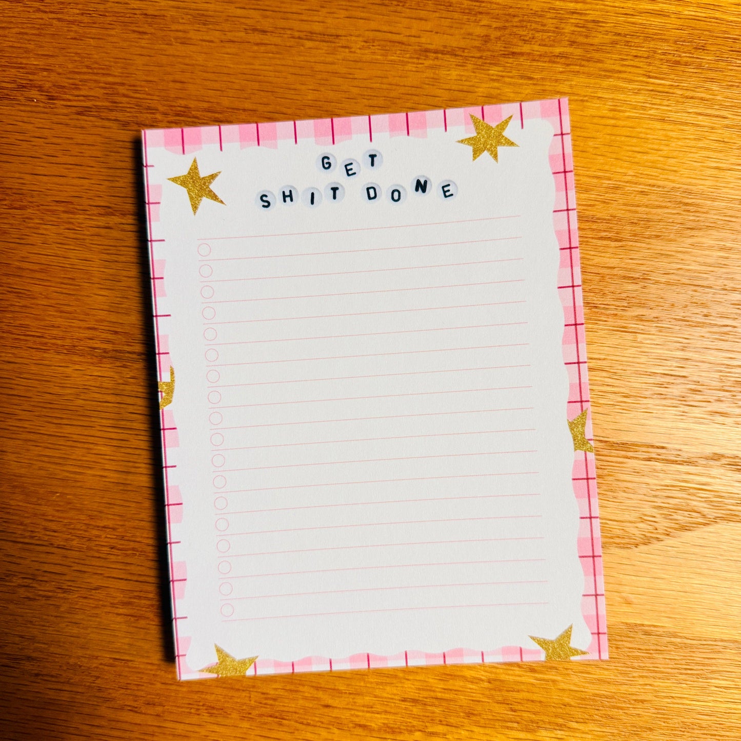 Notepad with 'GET SHIT DONE' text on a wooden surface