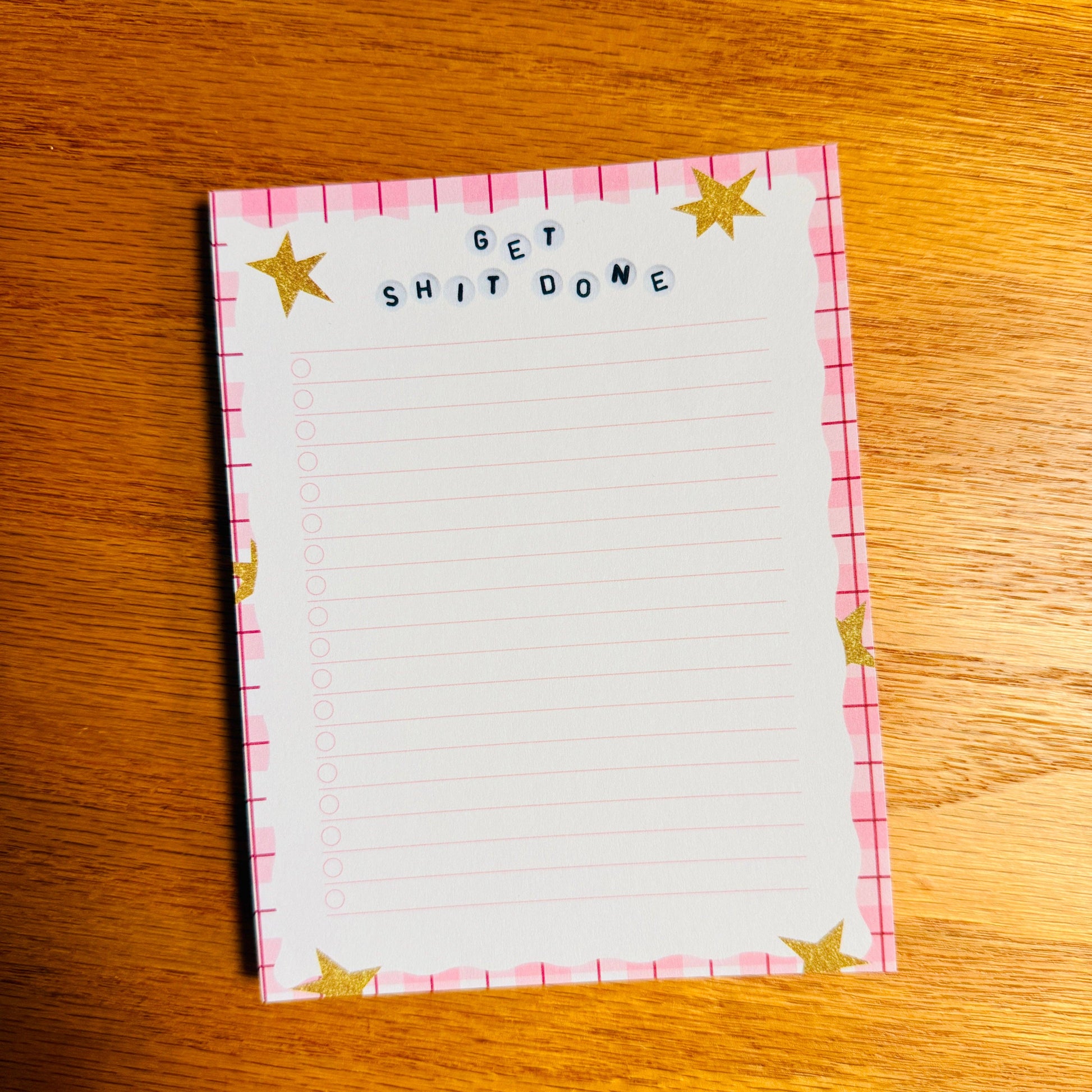 Notepad with 'GET SHIT DONE' text on a wooden surface