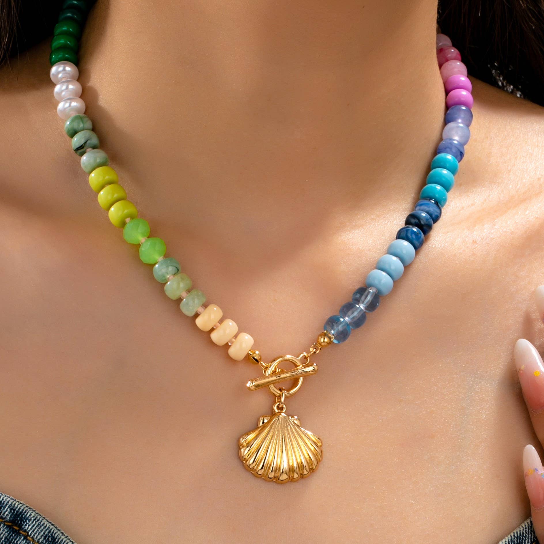 Colorful beaded necklace with a gold shell pendant on a person