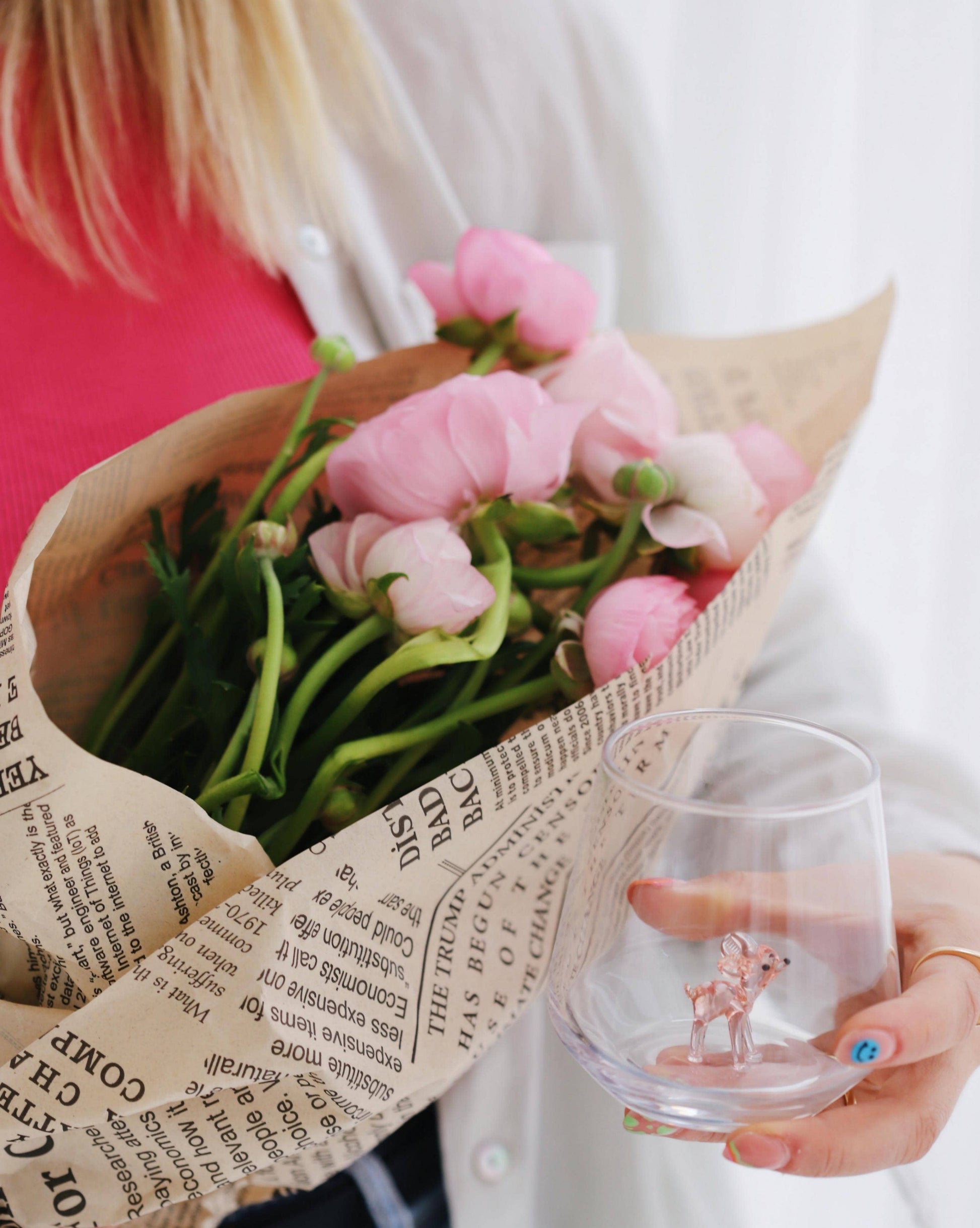 Bouquet of pink flowers wrapped in brown paper with a glass featuring a deer design.