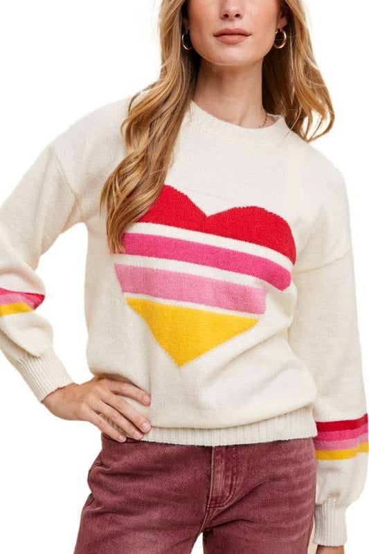 Woman wearing an ivory sweater with heart motif in the center made of 4 red, hot pink, light pink, and yellow stripes, and stripes of the same colors around the sleeves