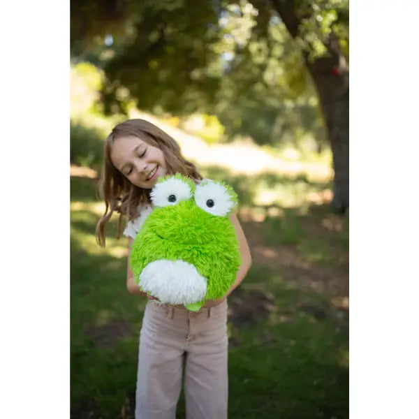 Child holding a green plush toy outdoors