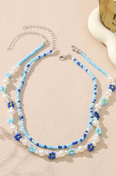 Beaded necklace with blue and white beads on a beige surface
