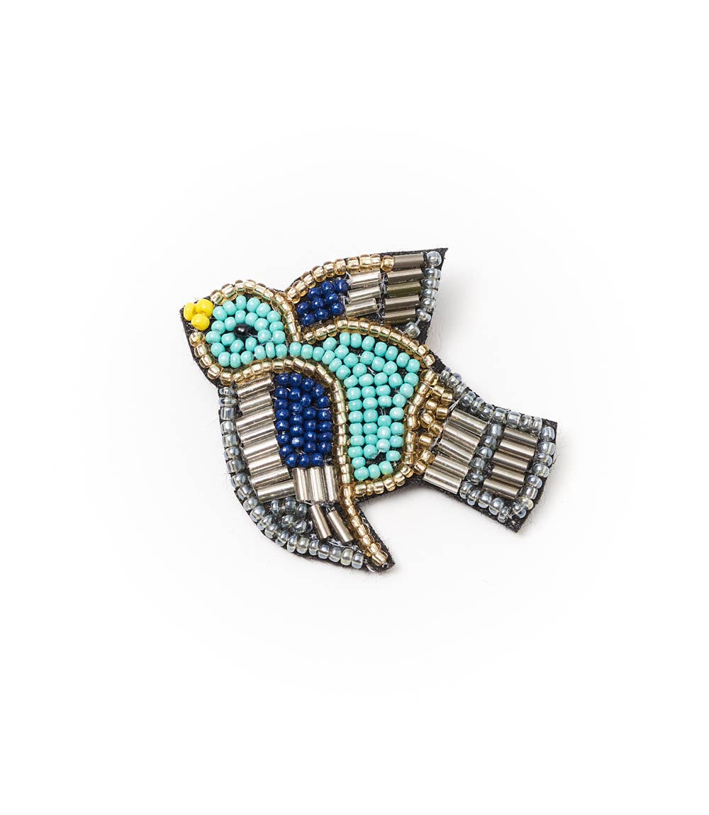 Decorative brooch with turquoise beads and blue stones on a white background