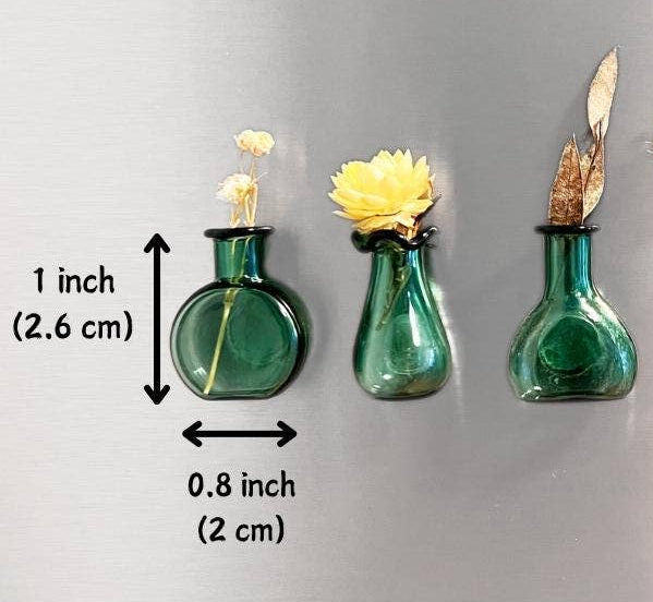 Five small green glass vases mounted on a metallic silver surface, each holding dried or artificial flowers. Black measurement arrows and text indicate the height and width of the leftmost vase as 1 inch (2.
