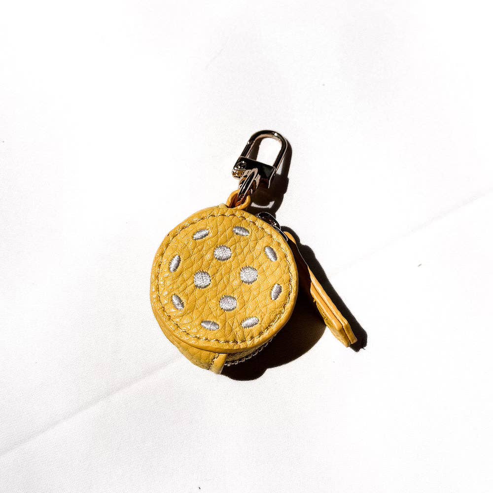 Yellow circular keychain with cut-out design on a white background