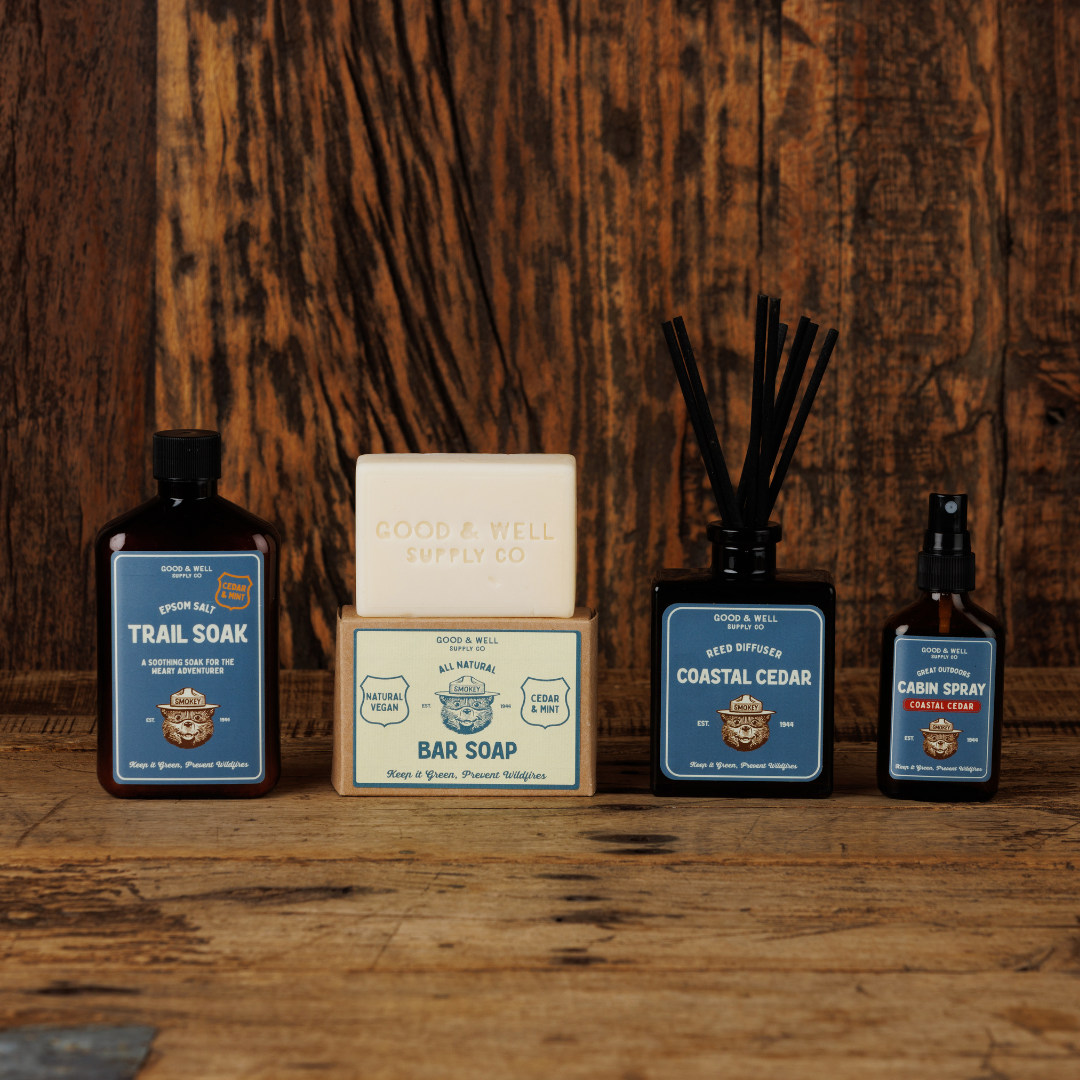 Collection of natural products including soap, diffuser, and spray bottles on a wooden surface with a rustic background.
