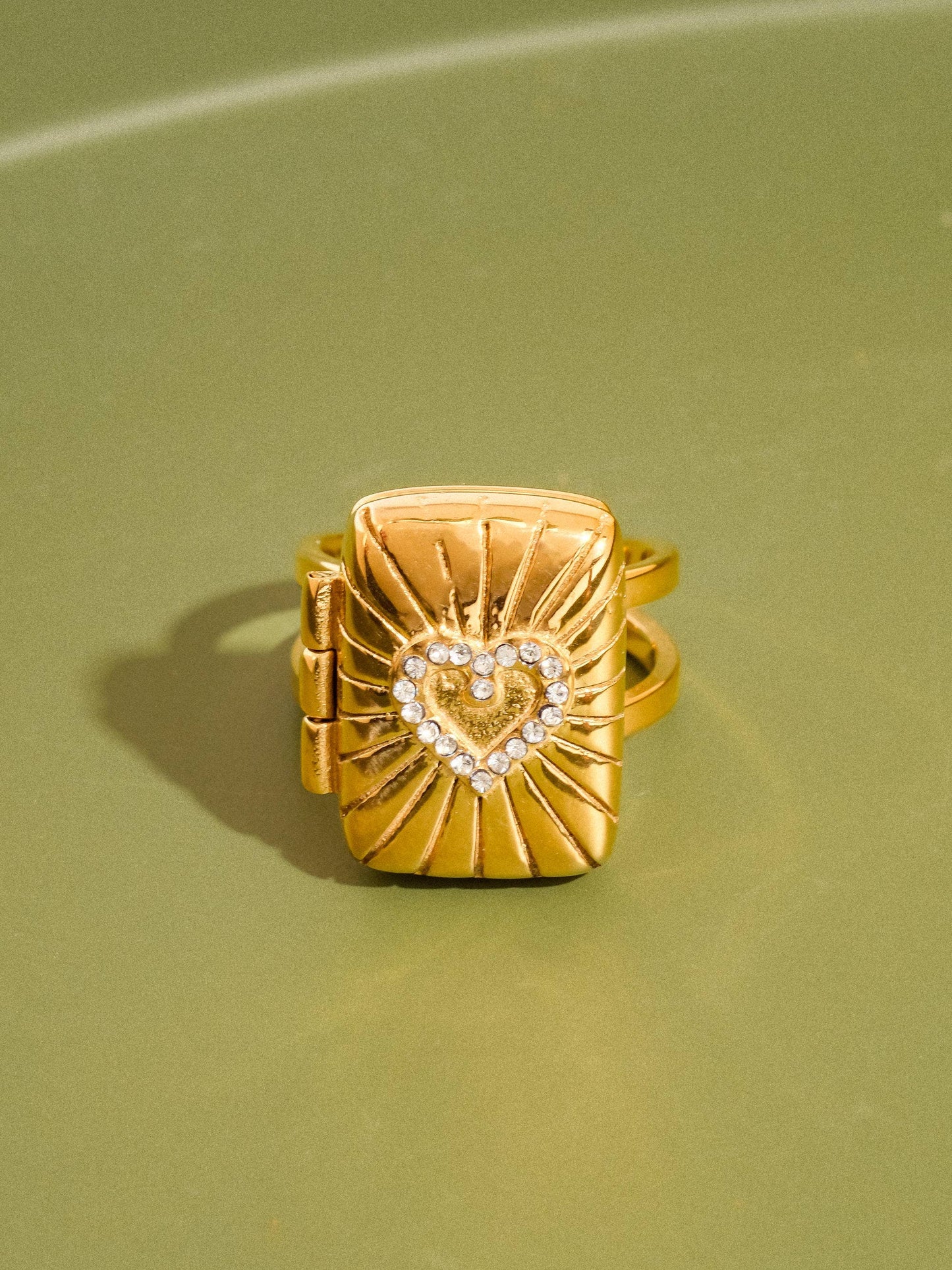 Gold ring with heart design on a green background