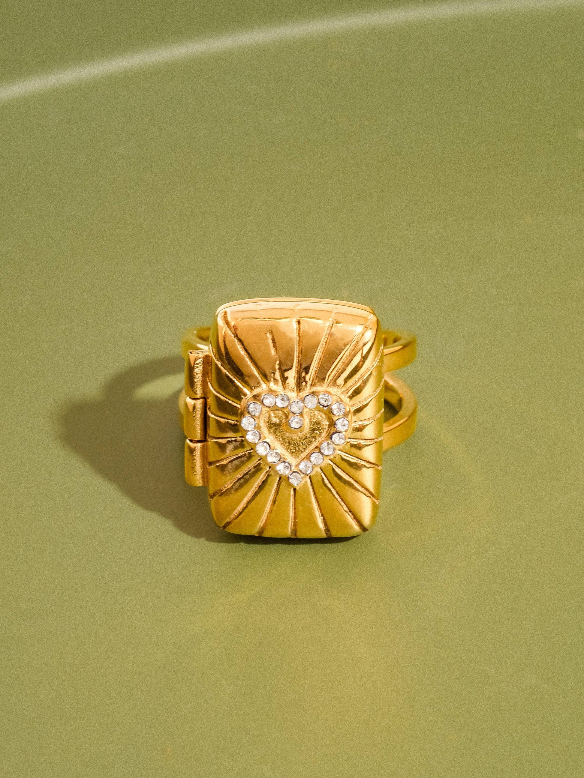 Gold ring with heart design on a green background