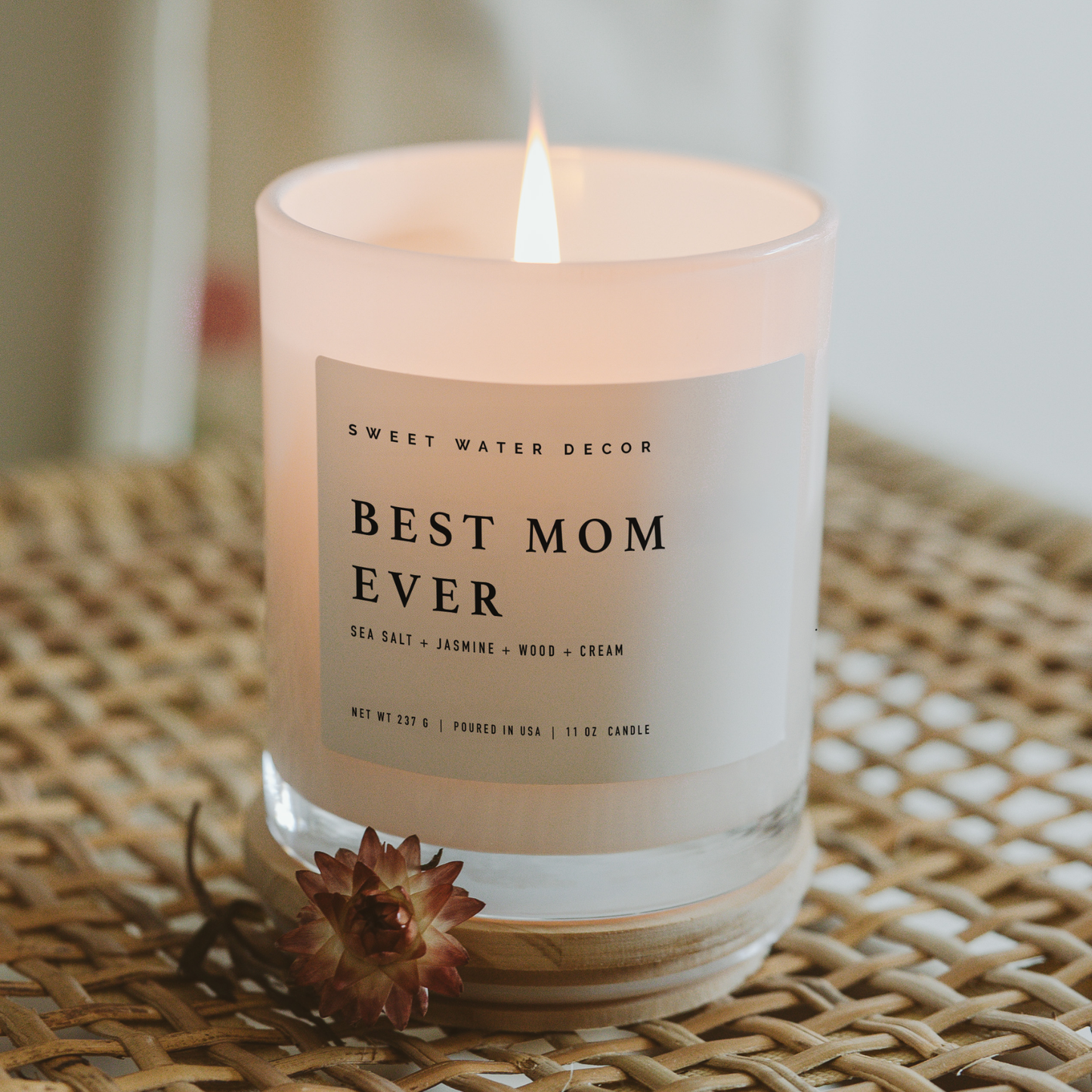 Candle with 'Best Mom Ever' label on a woven surface