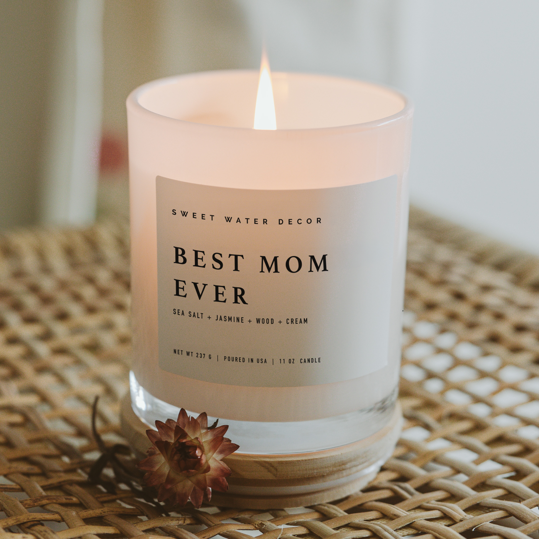 Candle with 'Best Mom Ever' label on a woven surface