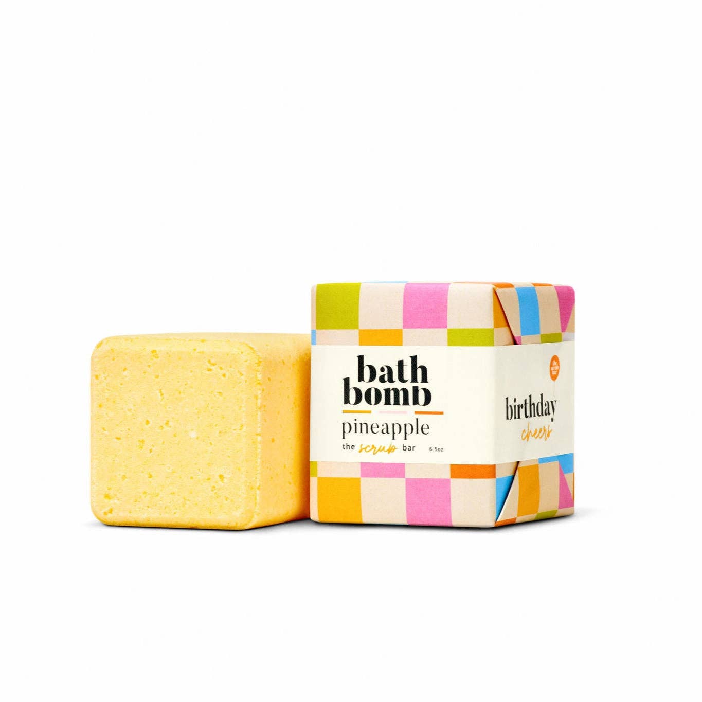 Yellow bath bomb next to its colorful checkered packaging on a white background