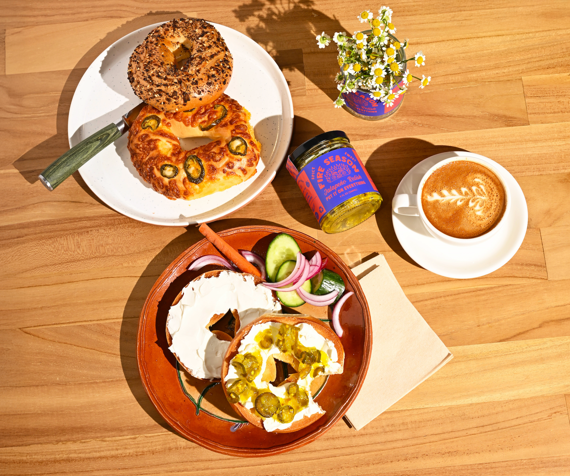 Breakfast setting with bagels, coffee, and condiments on a wooden table.