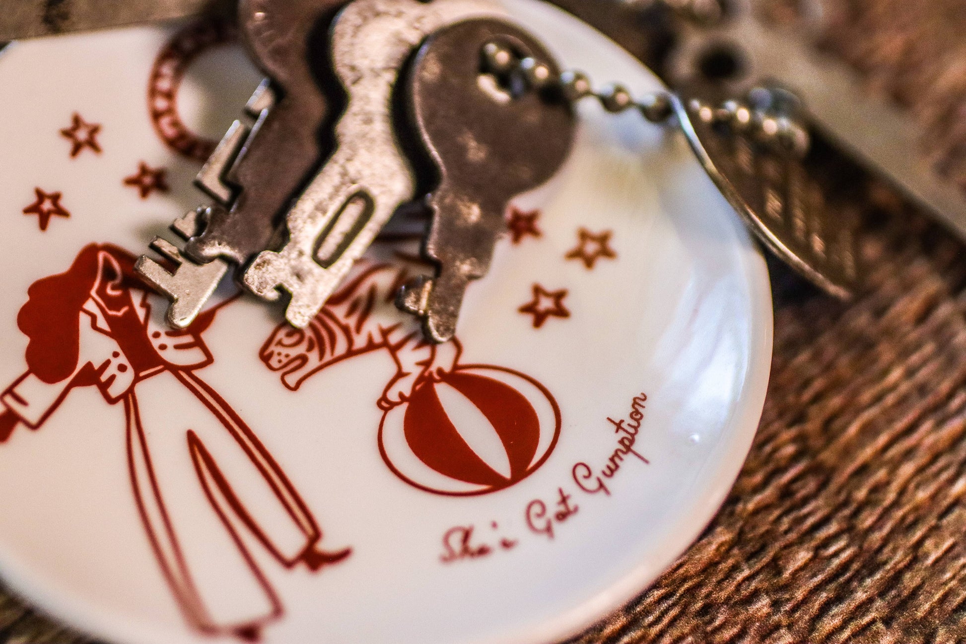 Decorative keychain with cartoon characters and text on a wooden surface