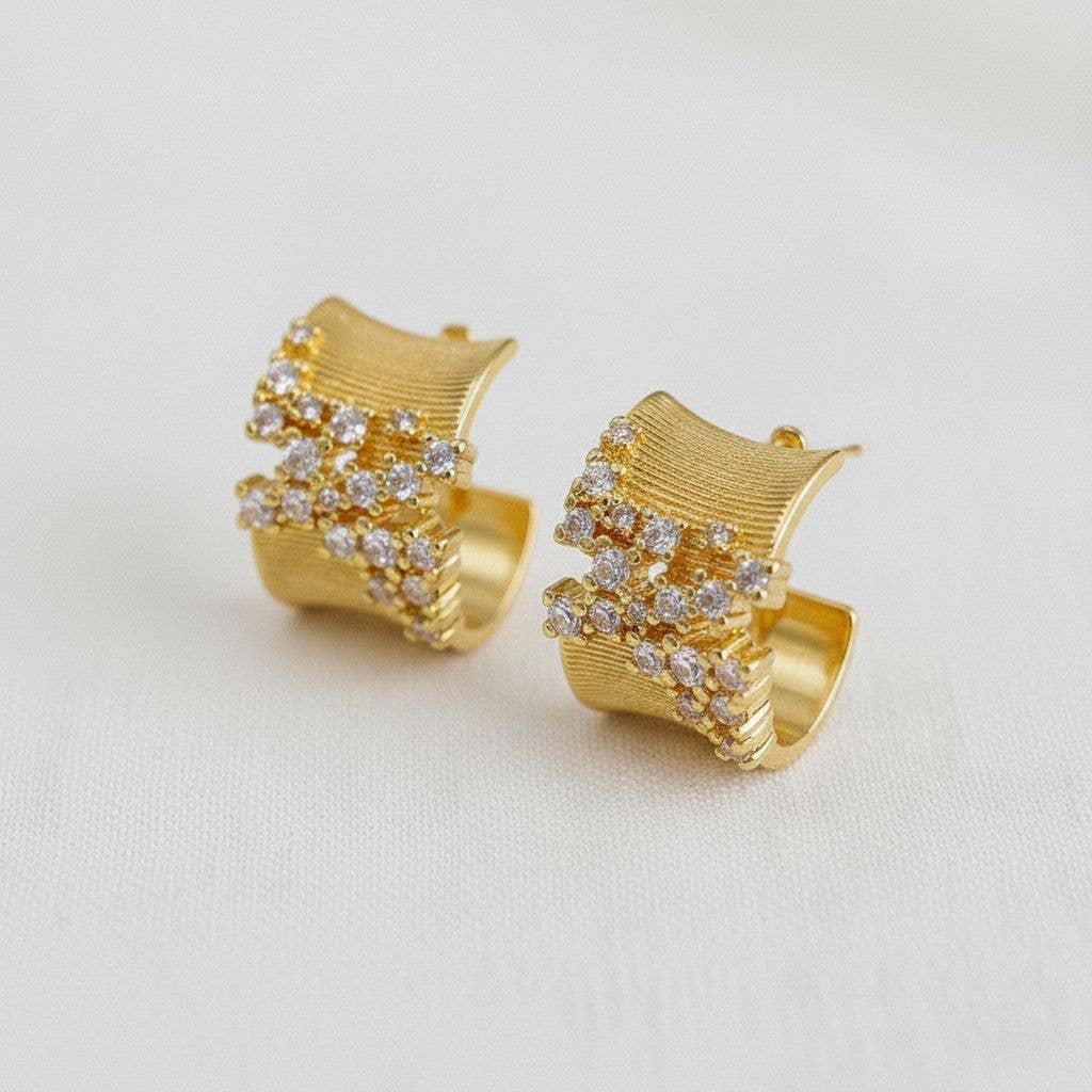 Gold hoop earrings with diamond accents on a light gray background