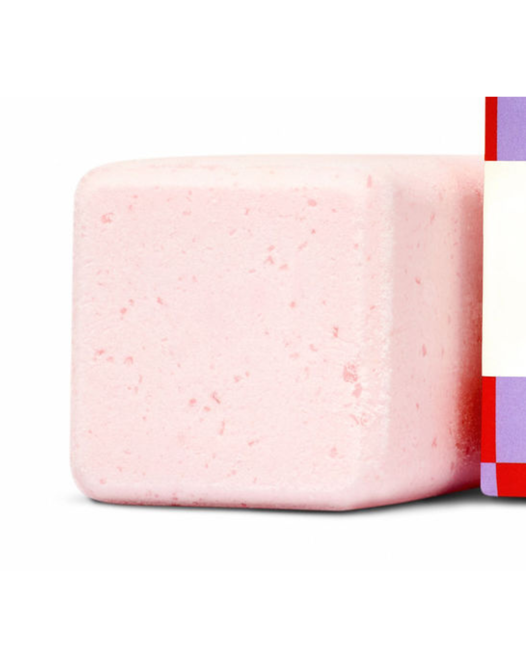 Close-up of a pink bath bomb with a colorful label on a white background