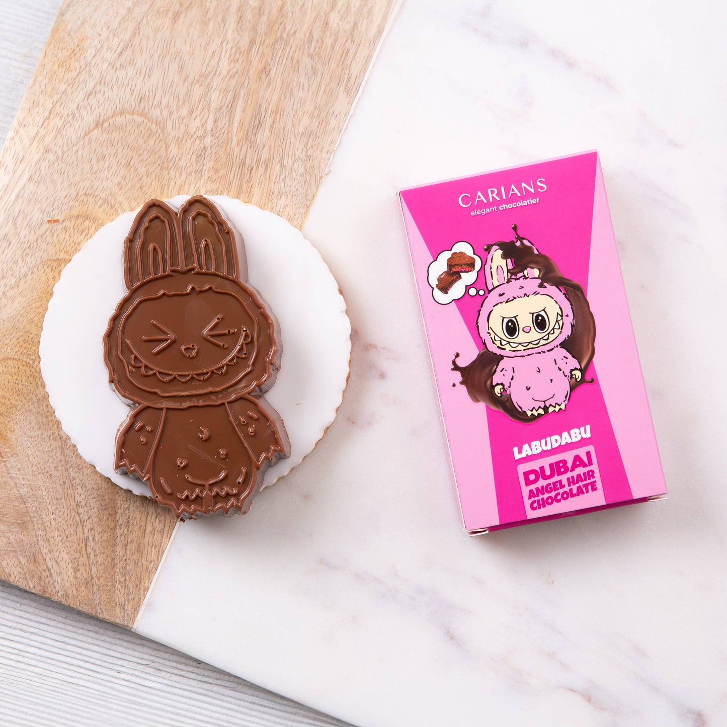 Chocolate cookie shaped like a character next to a pink Carians packaging on a marble surface