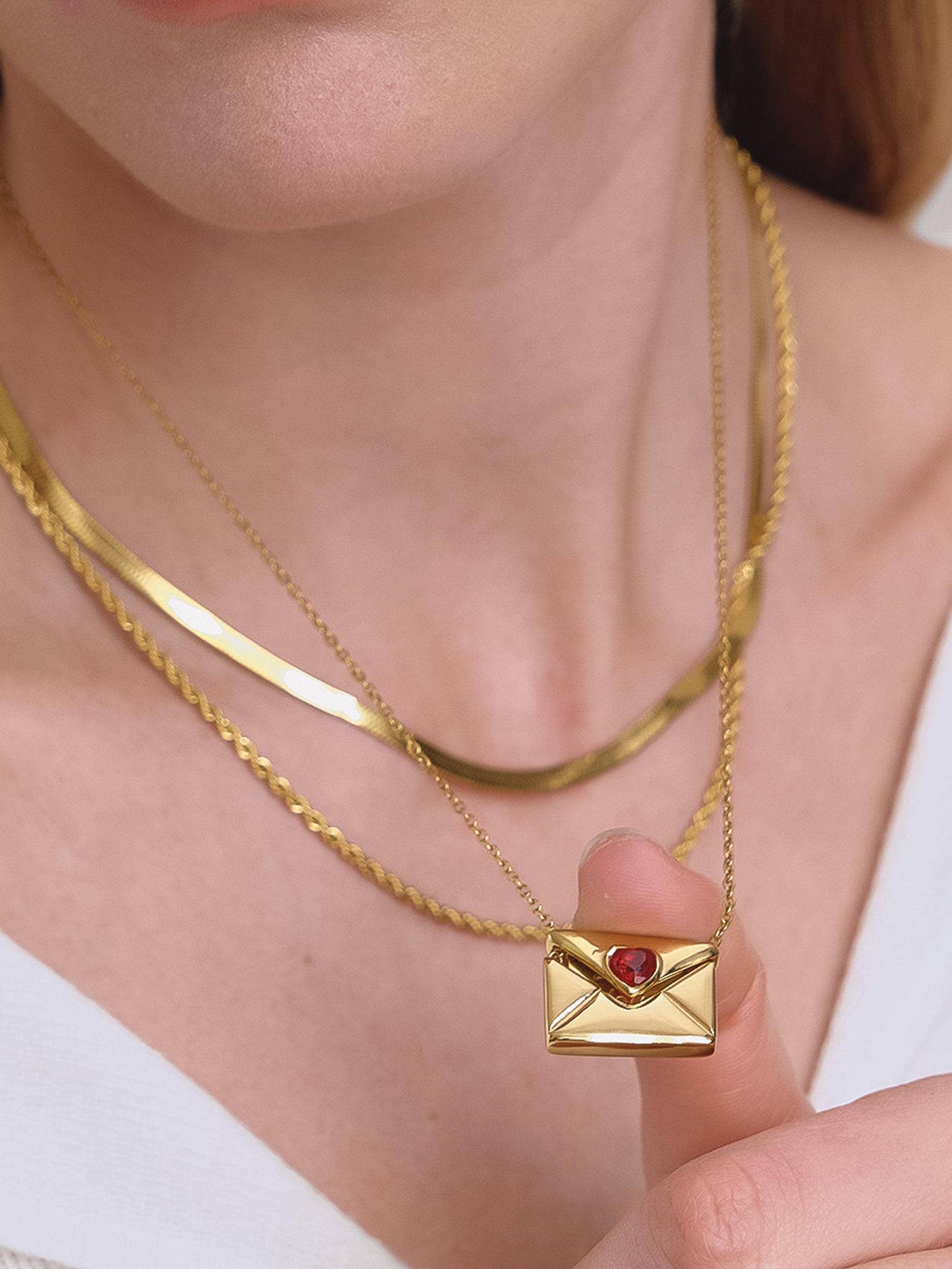 Gold necklace with a heart-shaped pendant worn by a person