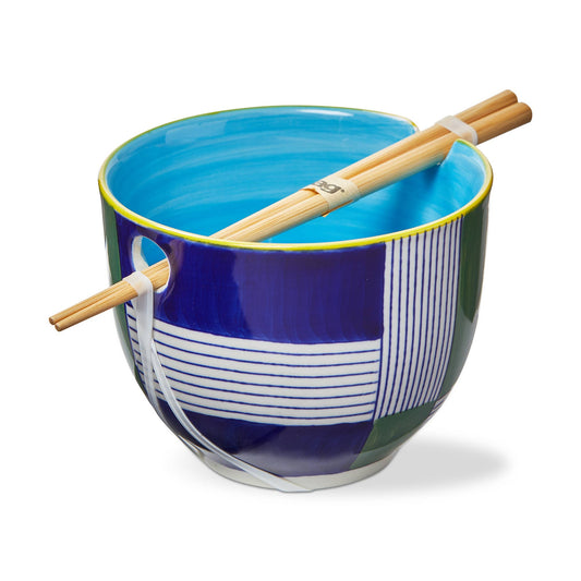 Noodlebowl with blue and green geometric stripe areas. The rim of the bowl is yellow and the interior is a lighter blue. A pair of chopsticks rests on top of the noodle bowl and they are sold as a set. On a white background.