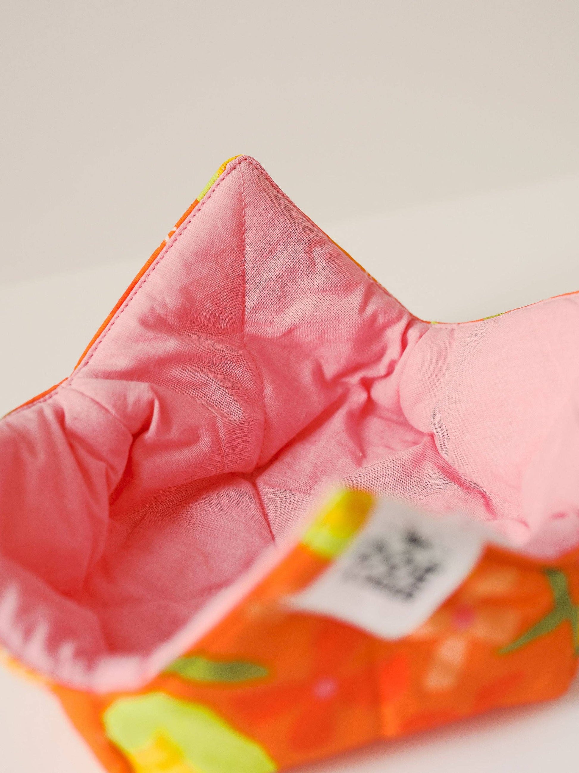Close-up of a pink baby seat with colorful patterns on a light background