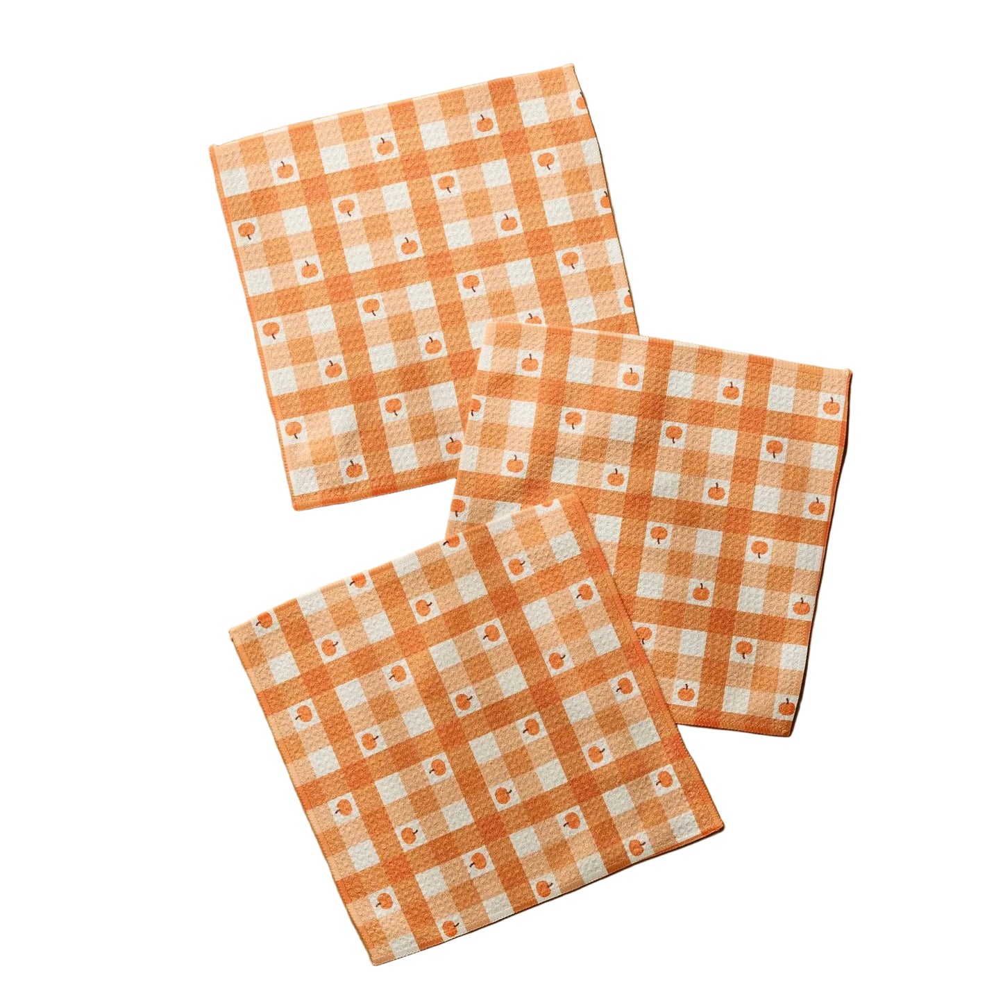 Three square cotton napkins with an orange and white gingham check pattern and small floral motifs, arranged on a light wood surface.
