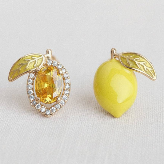 Pair of earrings with yellow gemstones and leaf designs on a light background