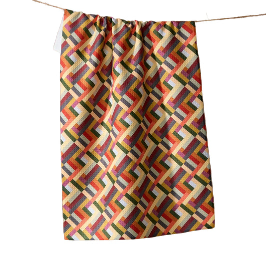 Colorful geometric patterned towel hanging on a line against a white background
