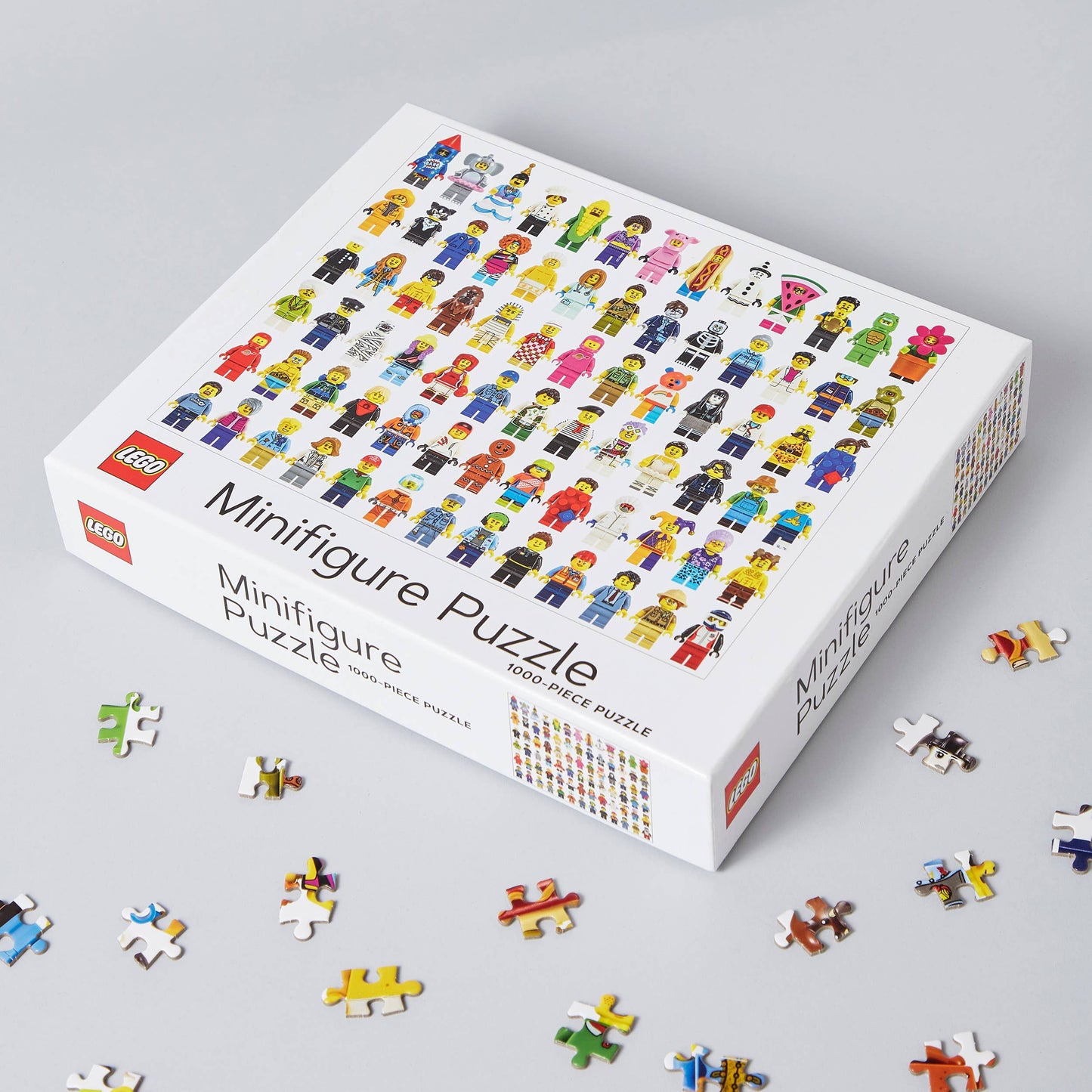LEGO minifigure puzzle box with scattered pieces on a gray background