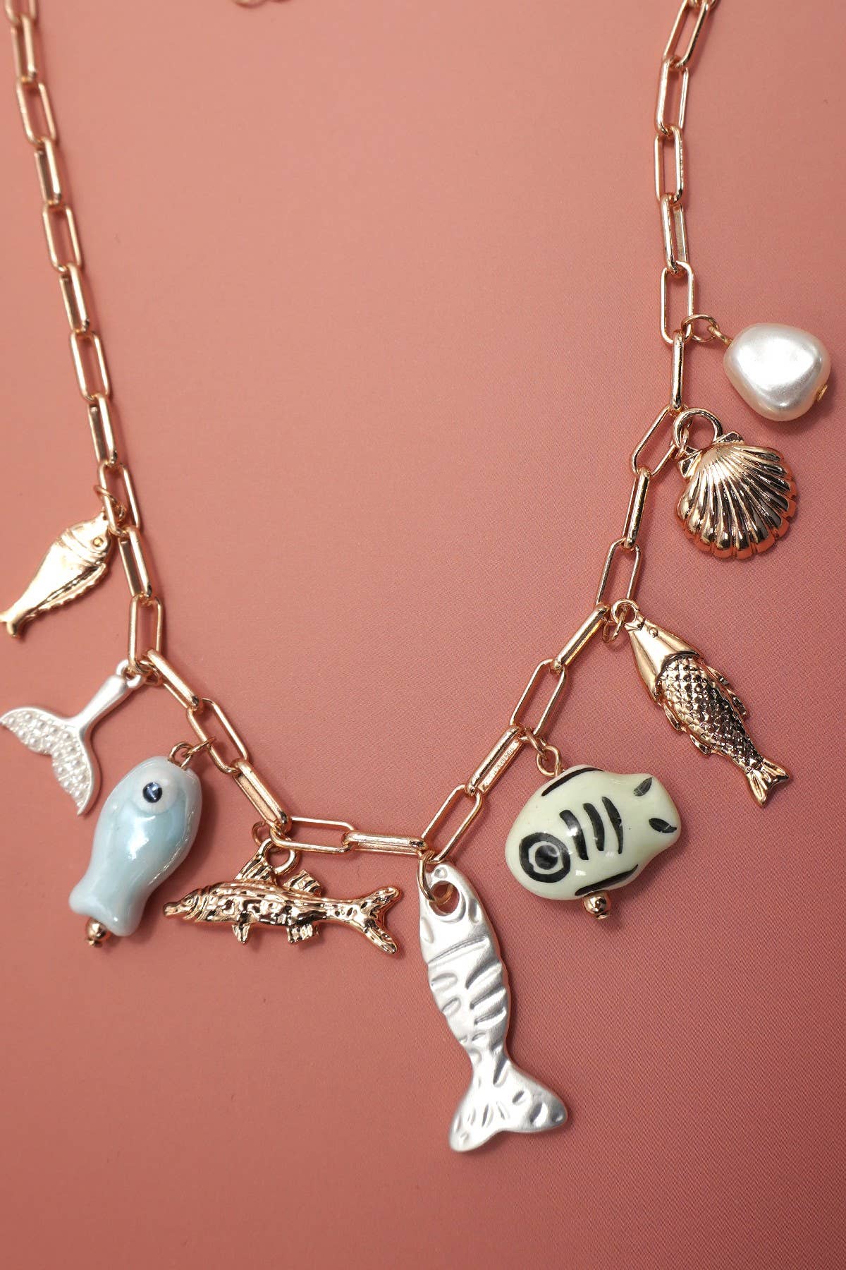 Necklace with various charm pendants on a pink background